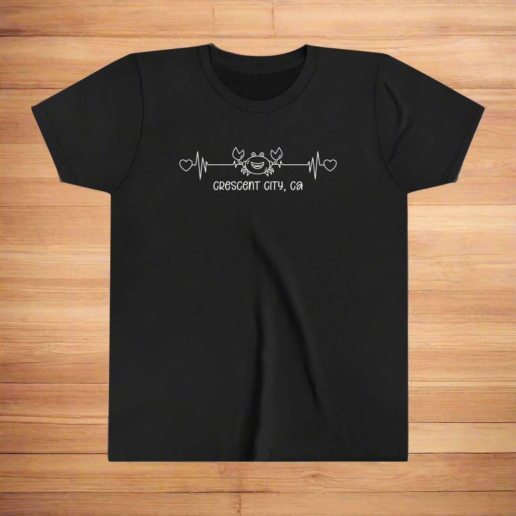 Black Youth t-shirt with a smiley crab on a heartbeat line with hearts at both ends and “Crescent City, CA” underneath the design.