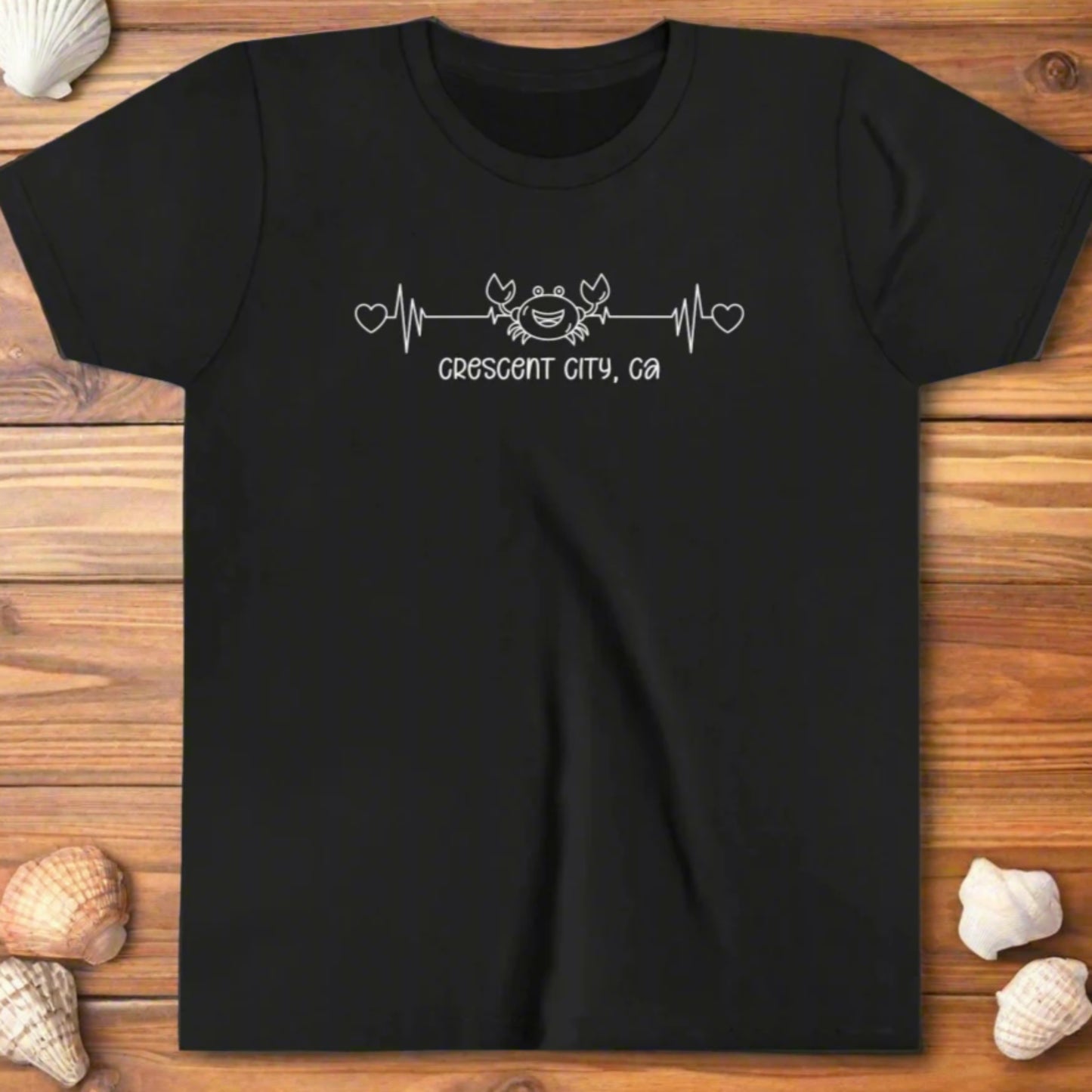 Black Youth t-shirt with a smiley crab on a heartbeat line with hearts at both ends and “Crescent City, CA” underneath the design.