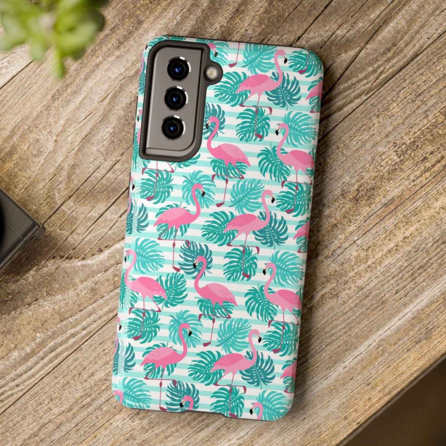 Phone case with flamingo and leaf pattern on a wooden surface