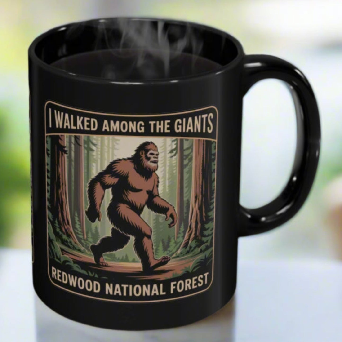 Black mug with a Sasquatch design and text 'I Walked Among the Giants, Redwood National Forest' on a blurred background.