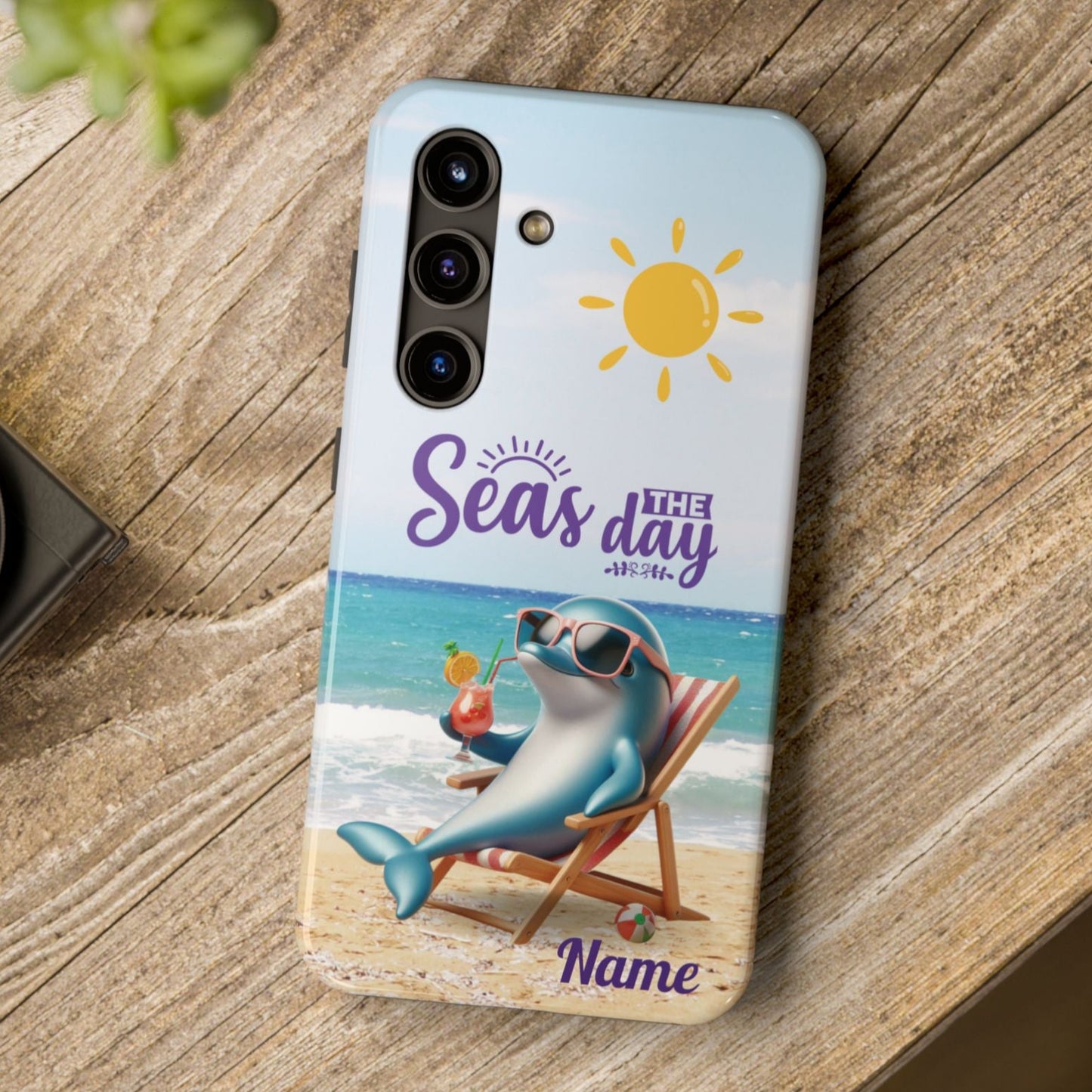 Seas the Day dolphin-themed phone case with personalized name, glossy finish, and beach-inspired design with a dolphin enjoying a cocktail during a sunny day on the beach with the phrase Seas the Day.