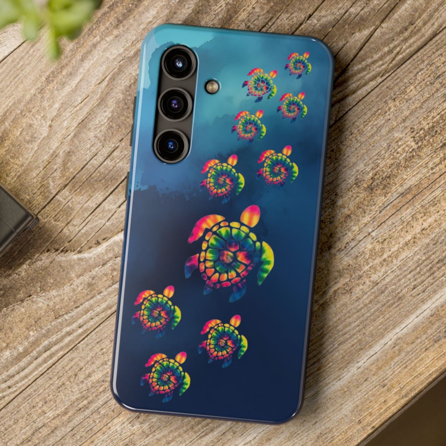Phone case with colorful turtle design on a wooden surface