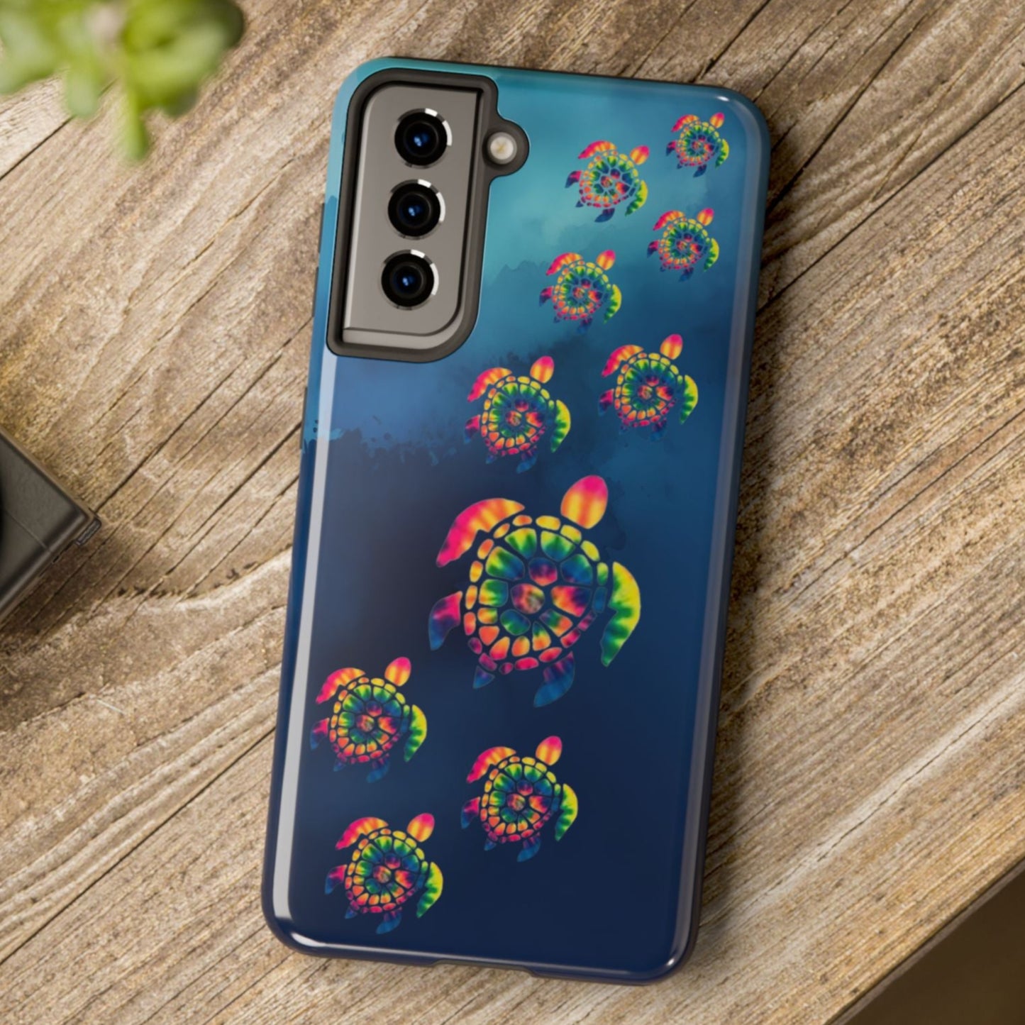 Phone case with colorful turtle design on a wooden surface