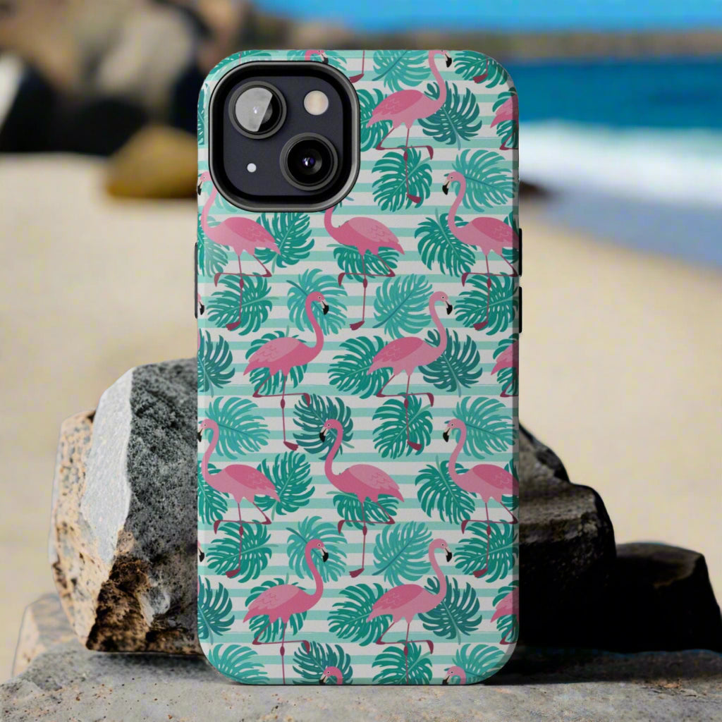 Phone case with flamingo and leaf pattern laying against rocks at the beach.
