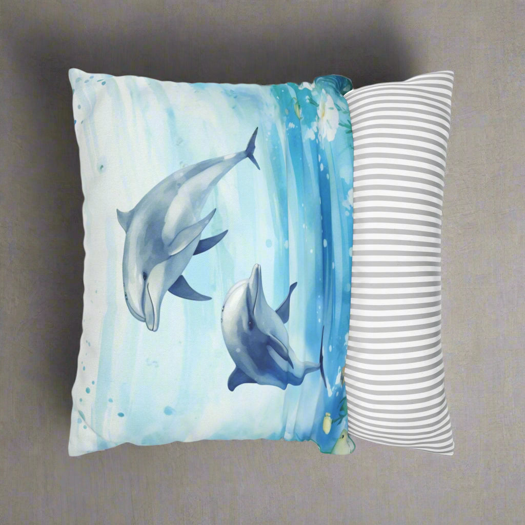 Decorative pillow cover with a watercolor design of two dolphins in the water with flowers along the bottom edges showing the ease of removal.