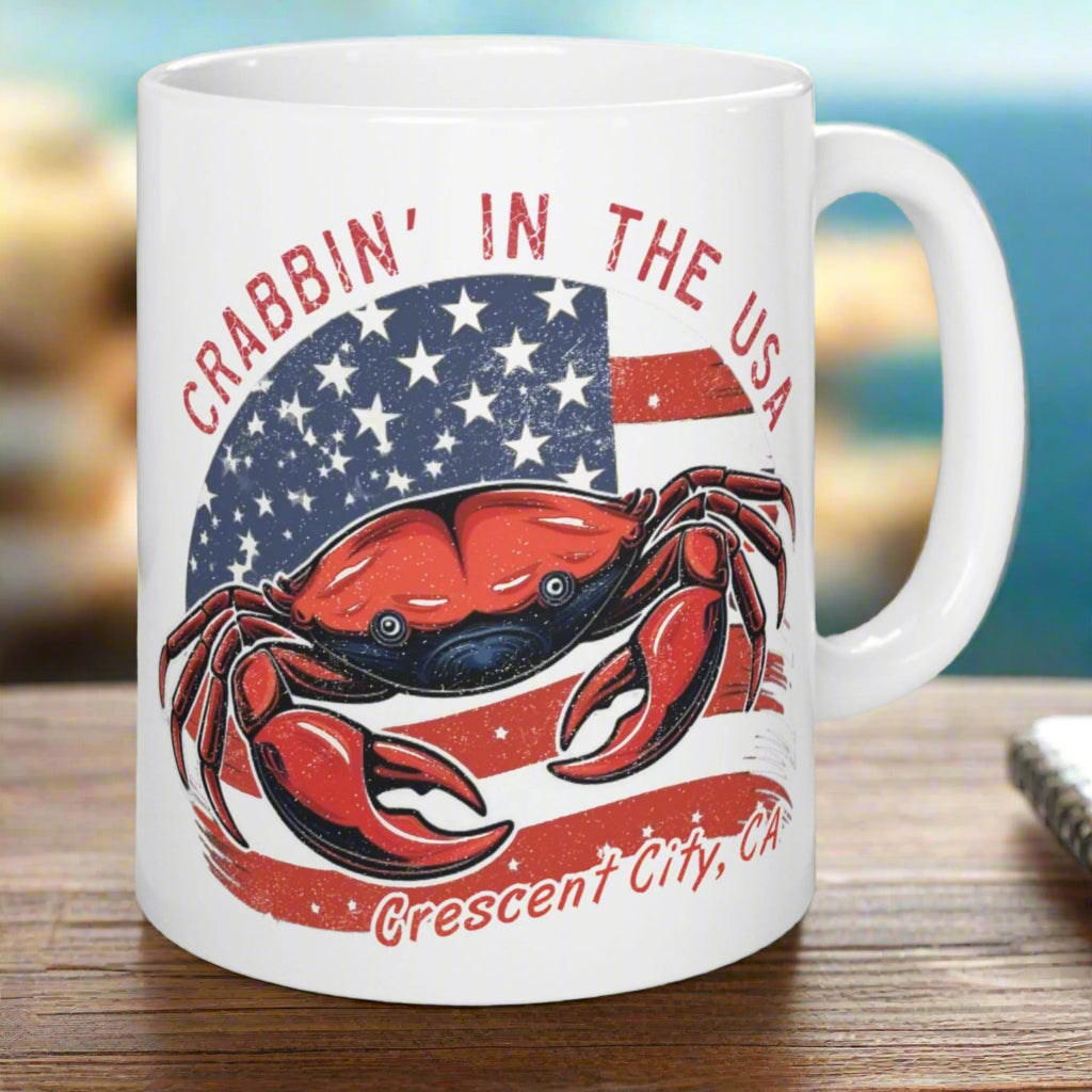 White mug with a red crab and American flag design with Crescent City, CA below.