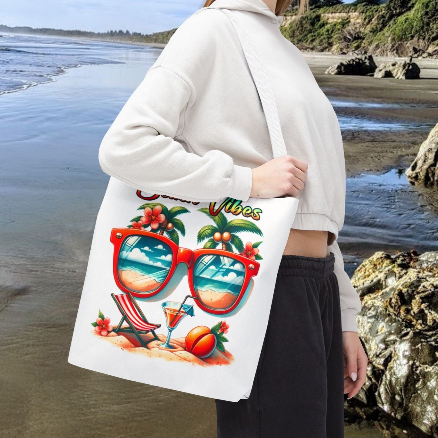 White 16" x 16 Tote bag featuring sunglasses with ocean and beach scene reflections, palm trees coming out of the glasses, a beach chair and cocktail on the sand, with the phrase "Beach Vibes" in a retro rainbow gradient font.