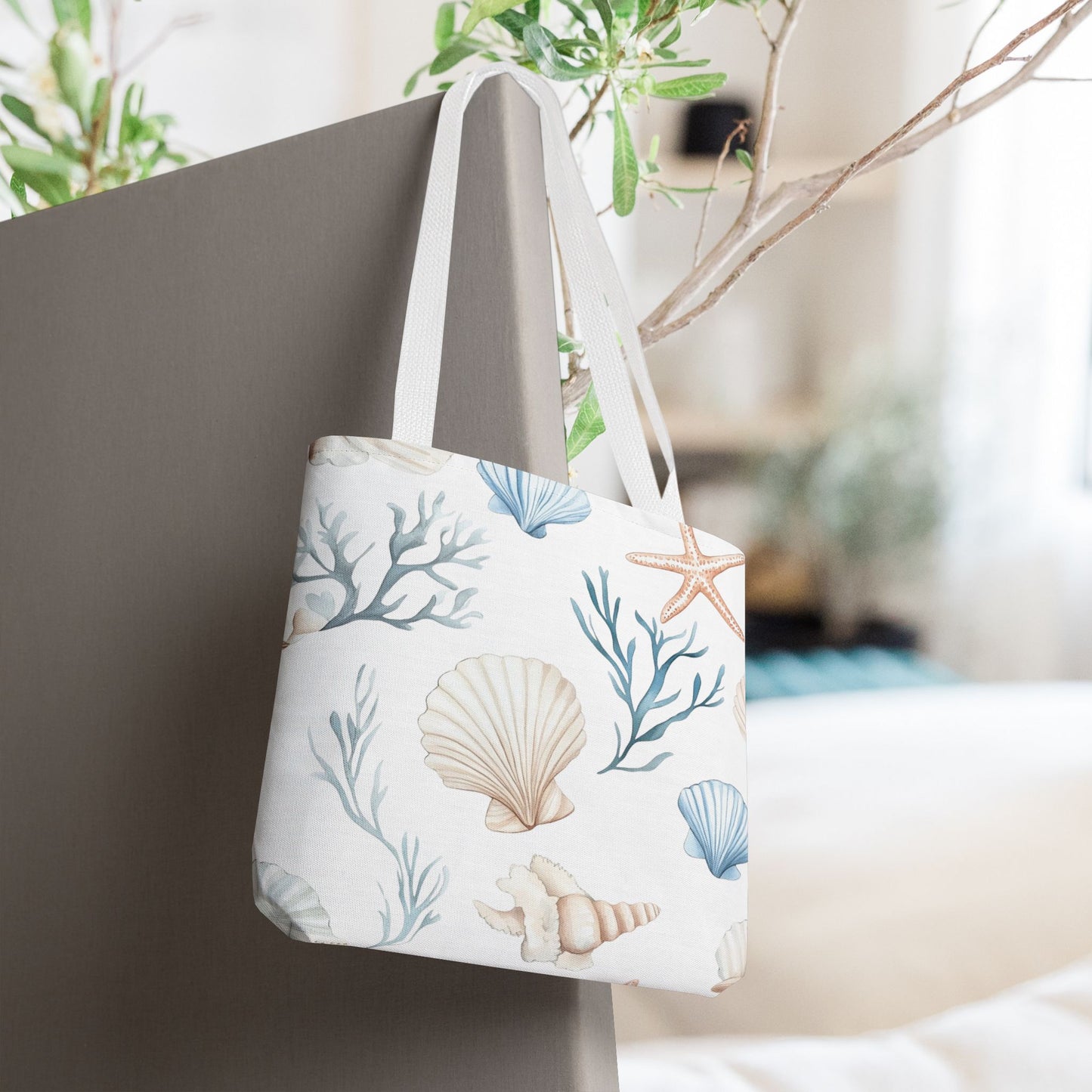 White tote bag with pastel blue and coral seashells, starfish, and underwater plants, with white handles.