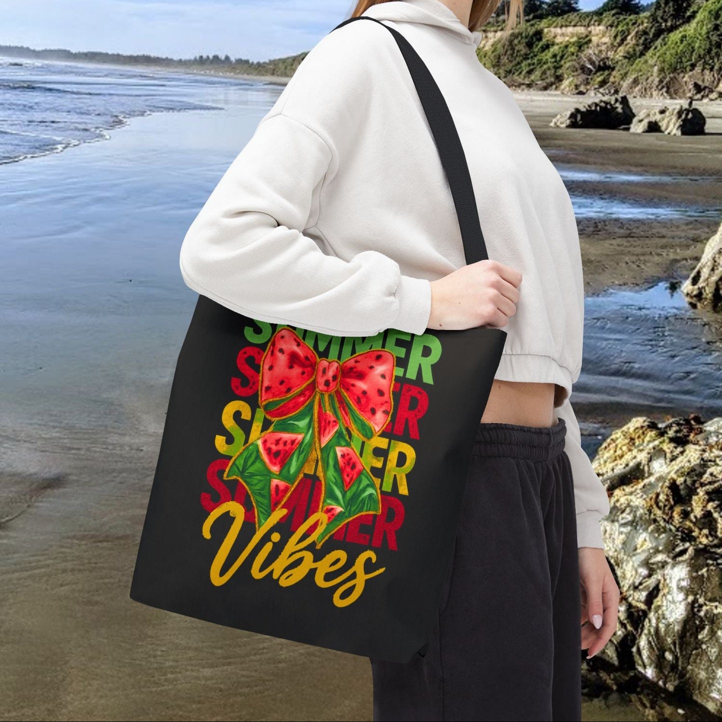 Black 16" x 16" tote bag with the word "Summer" repeated in green, red, and yellow, featuring a coquette-style bow, watermelon illustrations, and the word "Vibes" underneath.