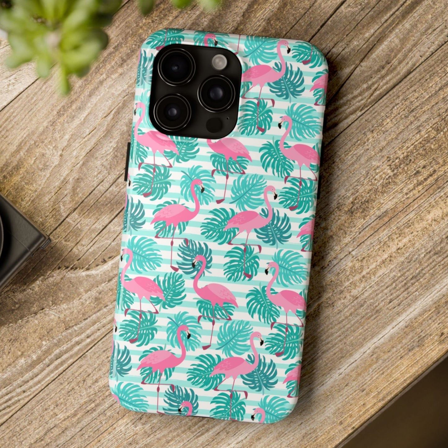 Phone case with flamingo and leaf pattern on a wooden surface