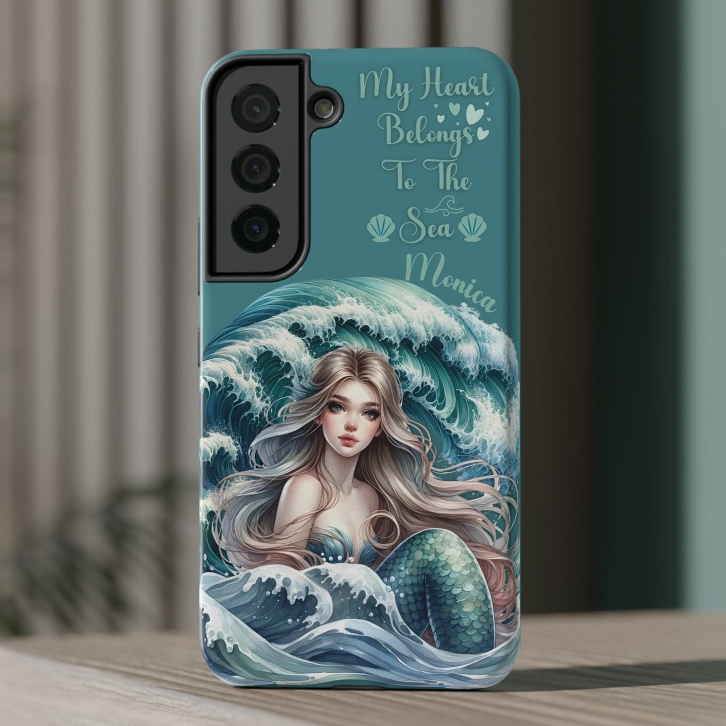 Phone case with mermaid design and text on a wooden surface