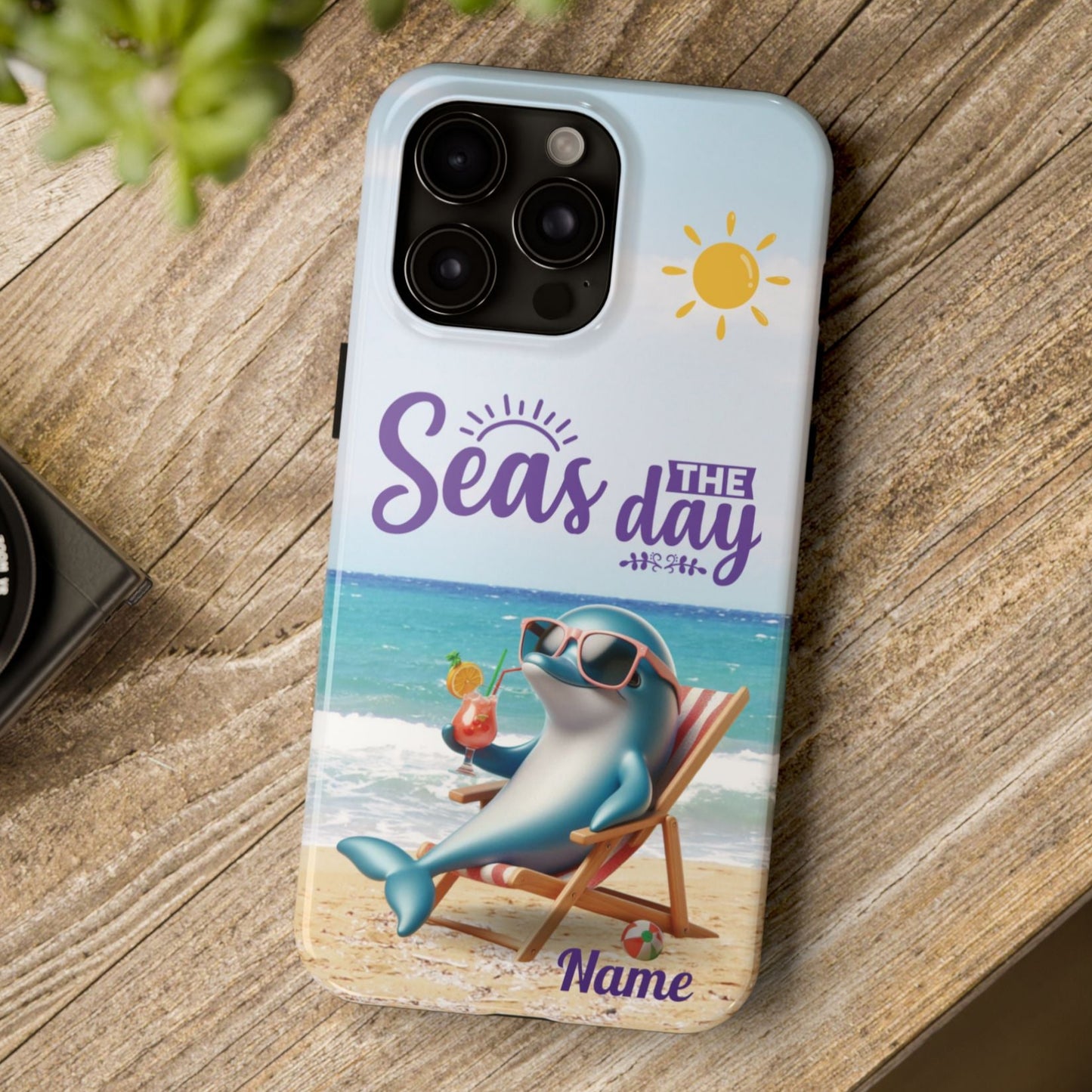 Seas the Day dolphin-themed phone case with personalized name, glossy finish, and beach-inspired design with a dolphin enjoying a cocktail during a sunny day on the beach with the phrase Seas the Day.
