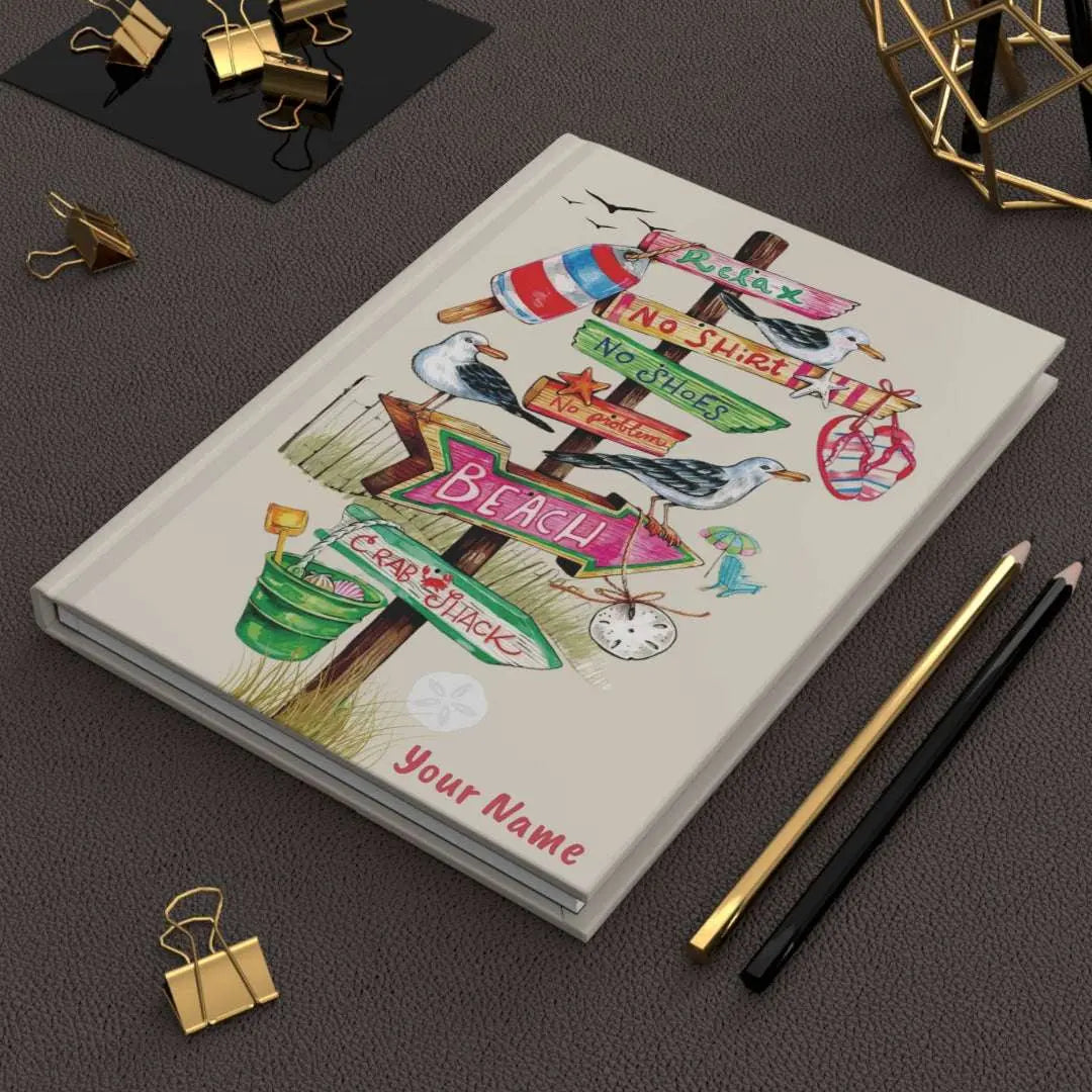 Personalized beach-themed hardcover journal featuring a beach-themed design with a direction wood sign with flip flops, sand bucket, and other beach items hanging off them, personalized with your name.