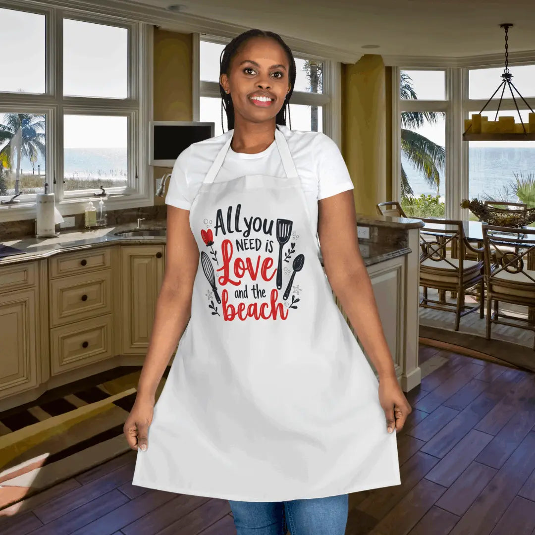White Beach-themed apron featuring the phrase 'All You Need is Love and the Beach' with utensil graphics. Made from durable, easy-to-clean fabric, this stylish apron is perfect for cooking, grilling, or beachside barbecues.