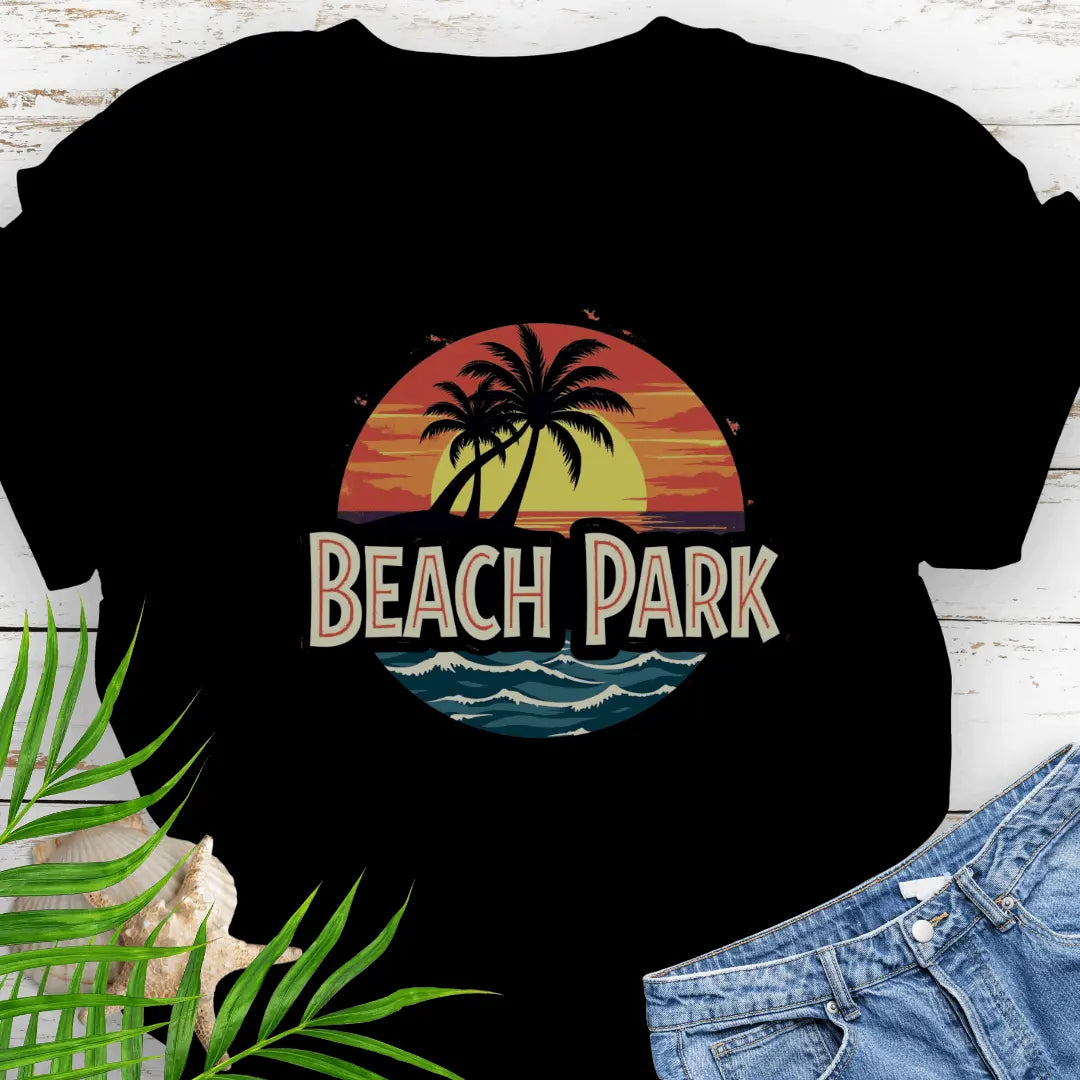 Black T-shirt with a vintage-style logo inspired by Jurassic Park, but with a beach theme featuring a circular emblem with a bold, retro font spelling 'BEACH PARK' in the center. The dinosaur silhouette is replaced with a tropical scene of palm trees.