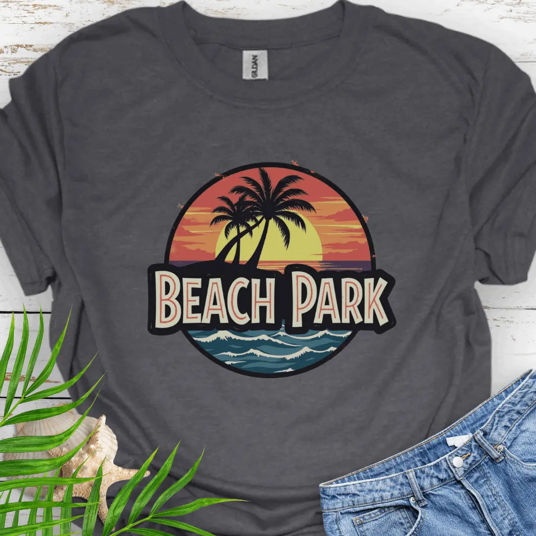 Dark Heather T-shirt with a vintage-style logo inspired by Jurassic Park, but with a beach theme featuring a circular emblem with a bold, retro font spelling 'BEACH PARK' in the center. The dinosaur silhouette is replaced with a tropical scene of palm trees.