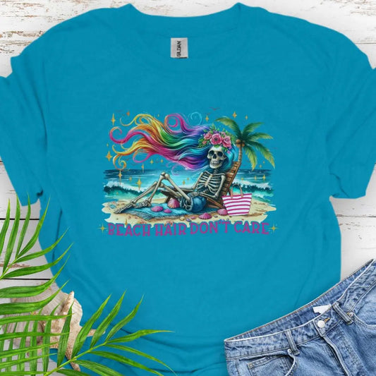 Tropical Blue T-shirt with a skeleton with rainbow hair flowing in the wind laying on a beach chair at the ocean that says Beach Hair Don't Care.
