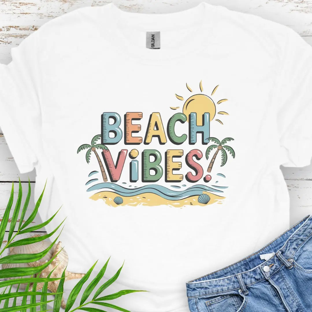 White T-shirt with colorful text Beach Vibes with a beach scene with palm trees and the sun.