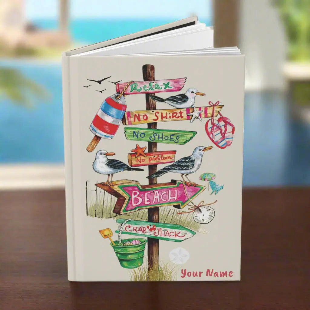 Personalized beach-themed hardcover journal featuring a beach-themed design with a direction wood sign with flip flops, sand bucket, and other beach items hanging off them, personalized with your name.