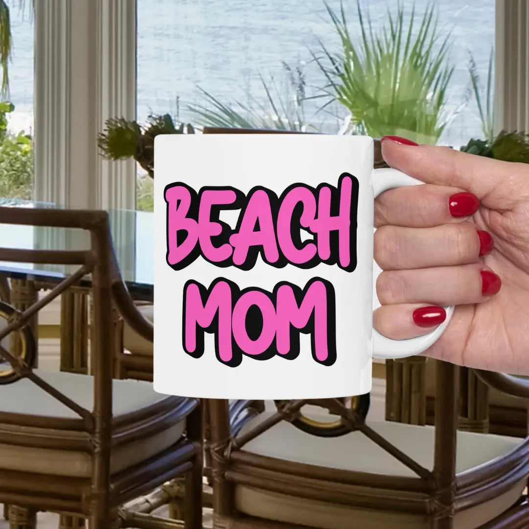 White 11 oz mug with a bright hot pink with black outline text Beach Mom.