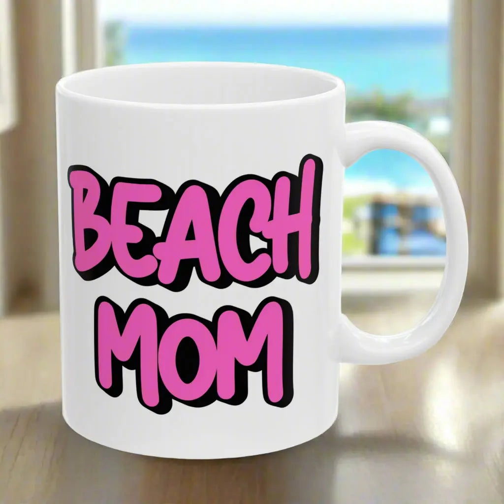White 11 oz mug with a bright hot pink with black outline text Beach Mom.