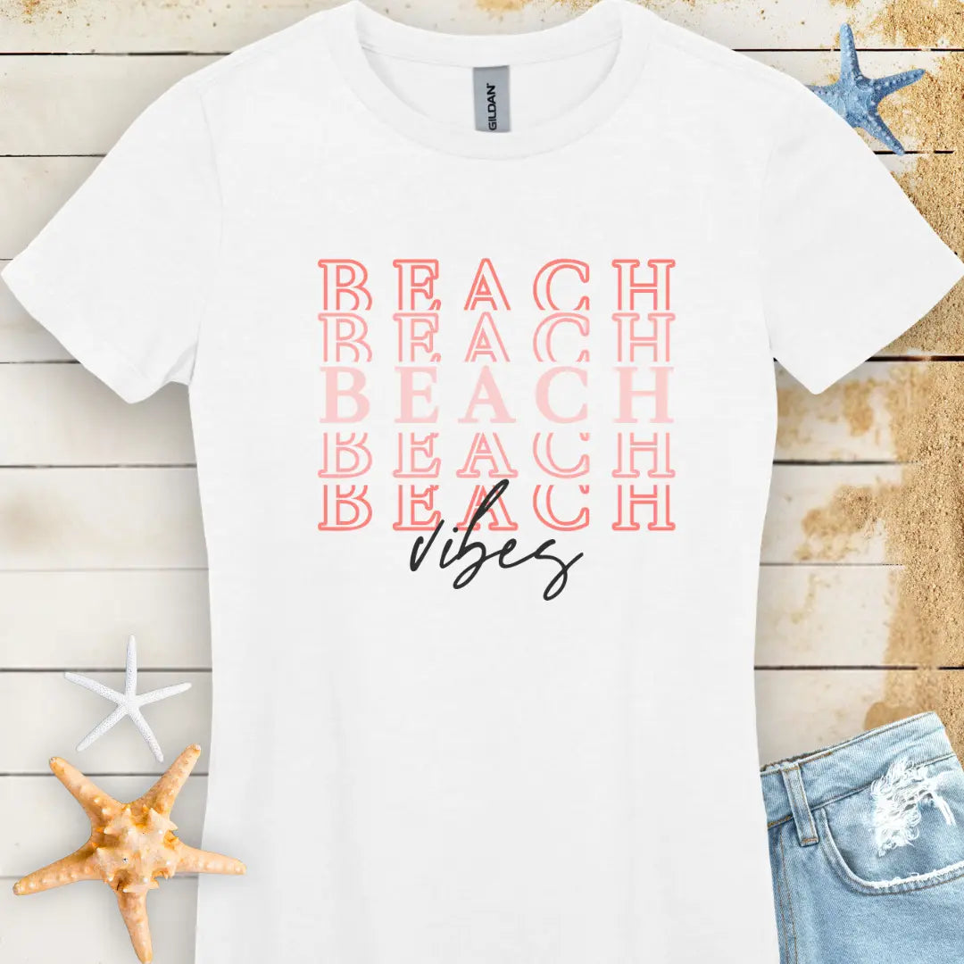 A white women's t-shirt with 'BEACH VIBES' printed in peach letters on the front.