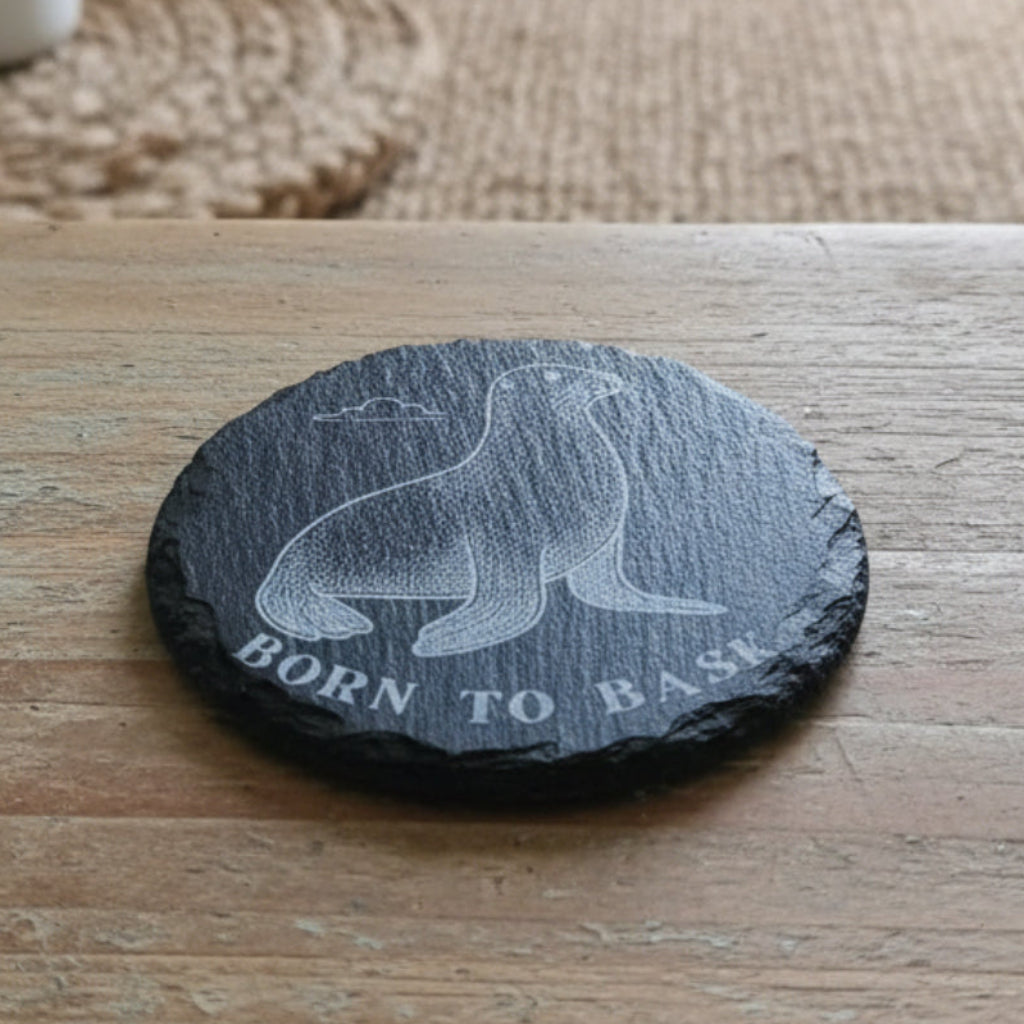 Black coaster with a seal illustration and 'Born to Bask' text engraved.