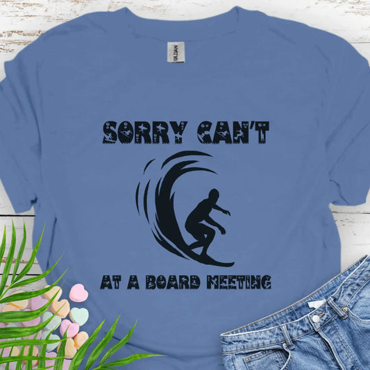 Indigo blue t-shirt with a surfer and says Sorry Can't Board Meeting - ideal for beach vacations, casual Fridays, and surfing enthusiasts.