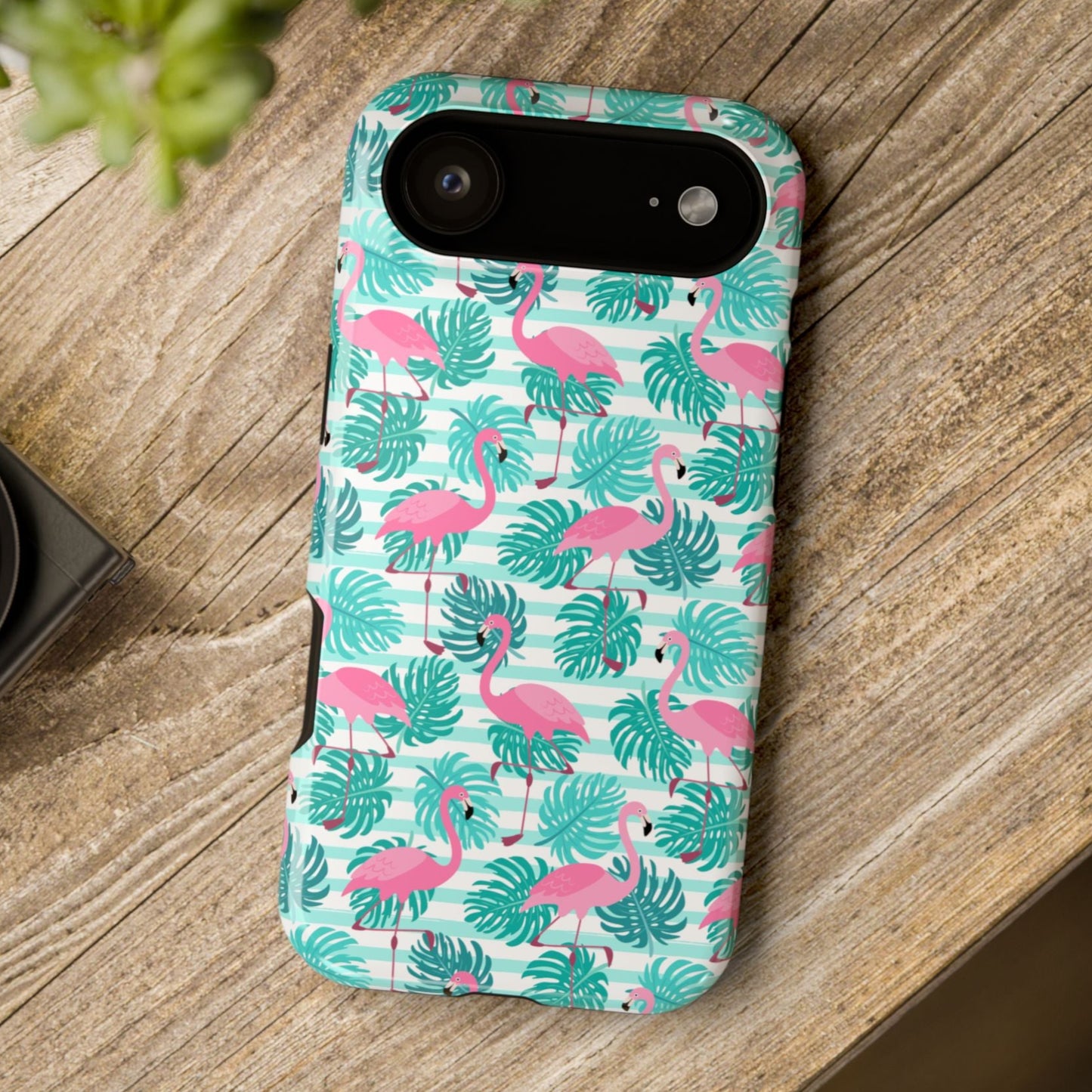 Phone case with flamingo and leaf pattern on a wooden surface