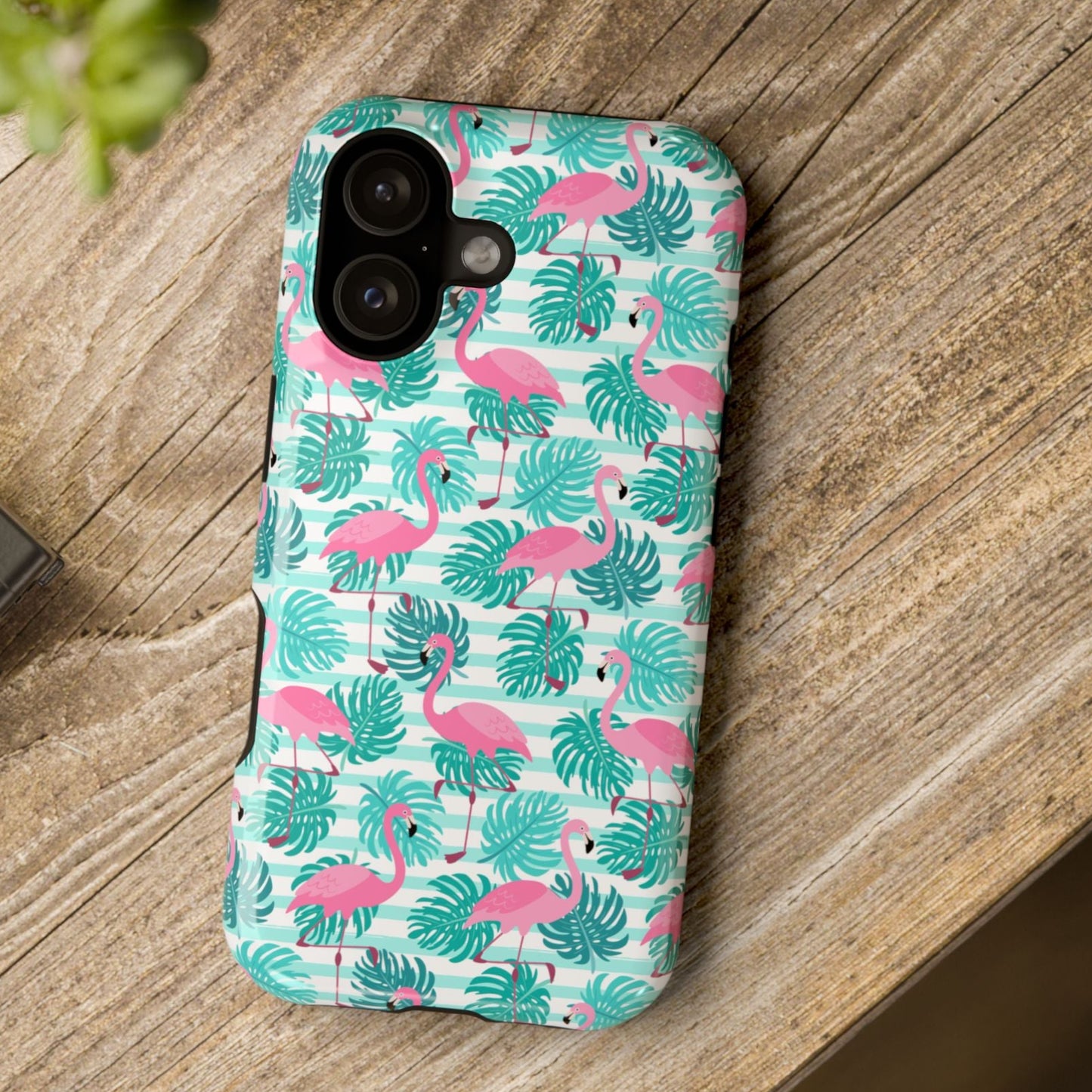 Phone case with flamingo and leaf pattern on a wooden surface