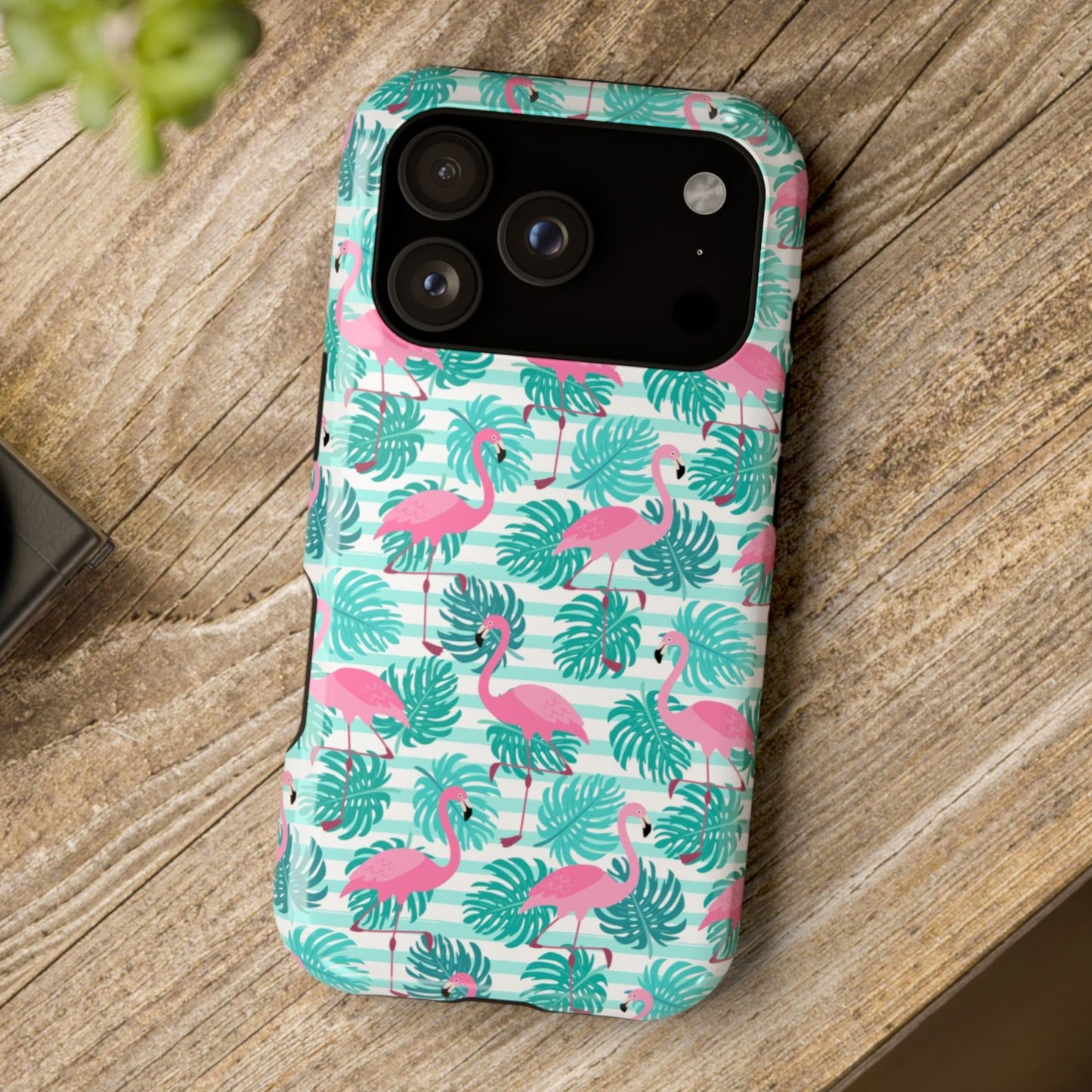 Phone case with flamingo and leaf pattern on a wooden surface