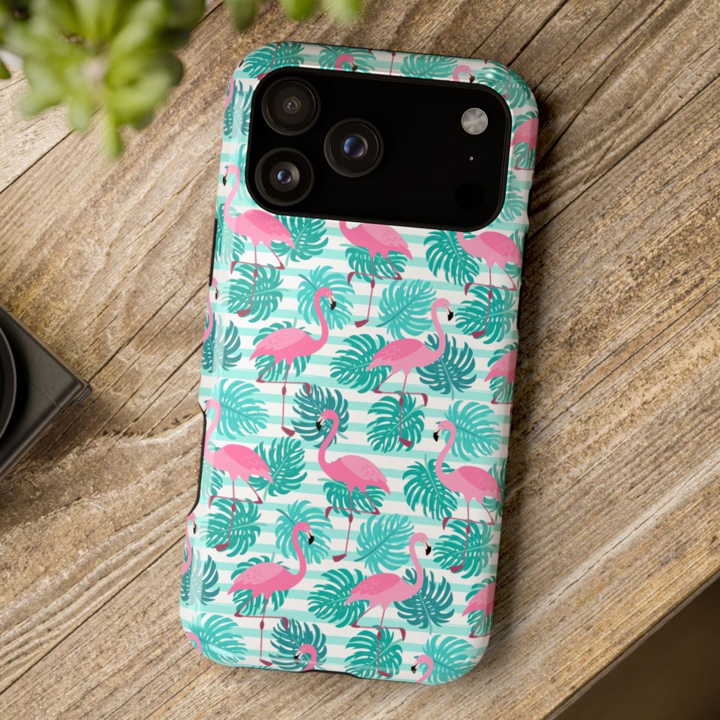 Phone case with flamingo and leaf pattern on a wooden surface