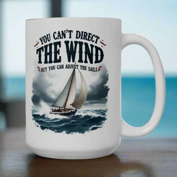 A white 15 oz. mug with a sailboat on the ocean with text 'You Can't Direct the Wind But You Can Adjust the Sails' with personalized name.