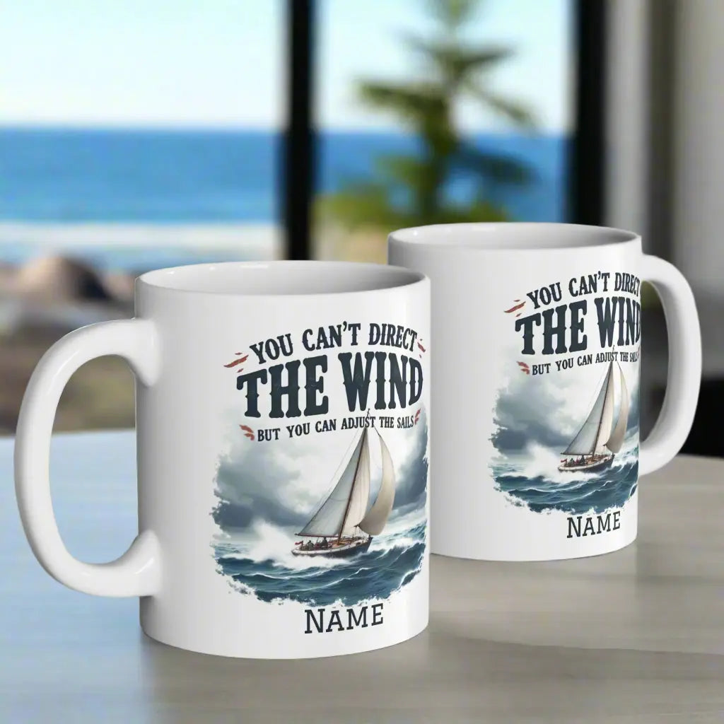 Two white 11 oz. mugs with a sailboat on the ocean with text 'You Can't Direct the Wind But You Can Adjust the Sails' with personalized name.