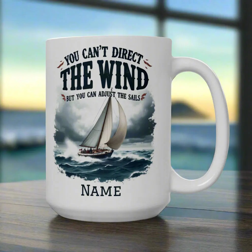 A white 15 oz. mug with a sailboat on the ocean with text 'You Can't Direct the Wind But You Can Adjust the Sails' with personalized name.