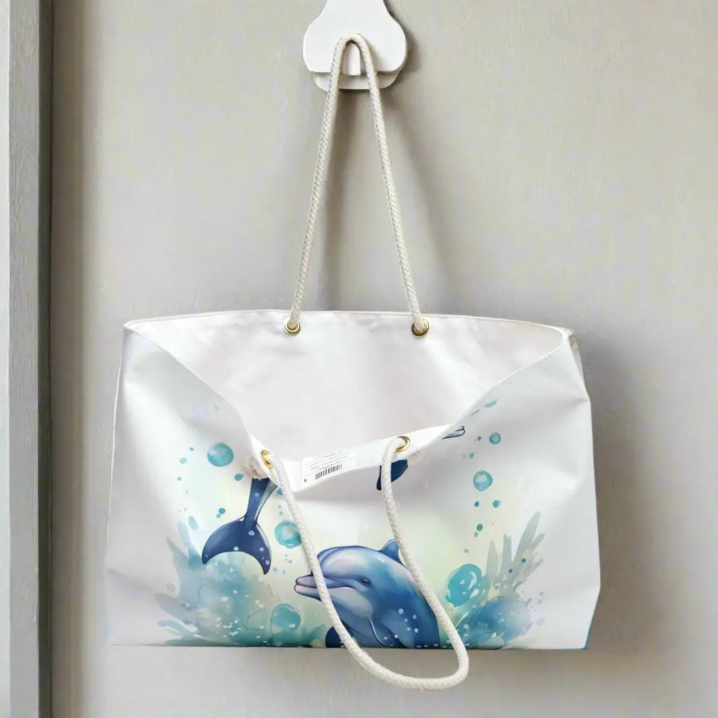 Our Dolphin Dancer Weekender Bag features two dolphins splashing out of the water with a white background. Large bag with durable rope handles help in with gold grommets. Perfect bag for weekend trips, beach bag, and summer vacation!