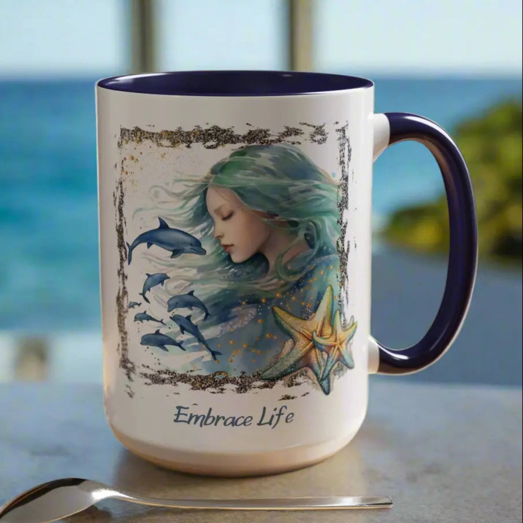White 15 oz Ceramic Mug with blue handle and inside with a mermaid and swimming dolphins gives a mystical and positive vibe with the text Embrace Life - ideal for those who love the beach and marine life!