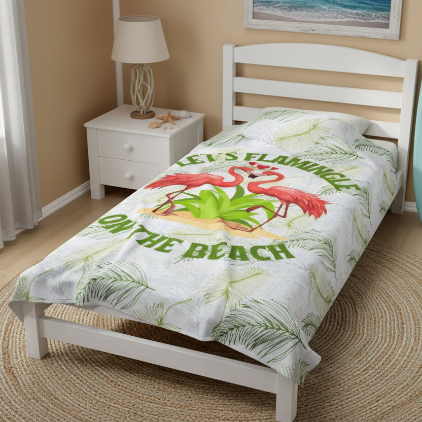 White velveteen plush blanket with green palm fronds and two flamingos in a heart shape that says Let's Flamingle. -perfect for snuggling on cold nights or as a comforting gift for a loved one who is a beach lover.