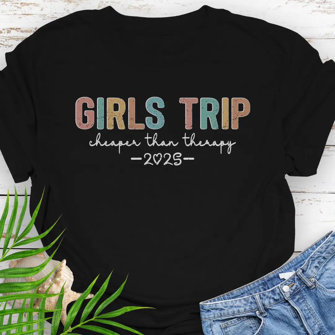 Black Girl’s Trip T-shirt with colorful grunge text, "Cheaper Than Therapy," and a customizable year. Perfect for group trips, fun getaways, and lasting memories.