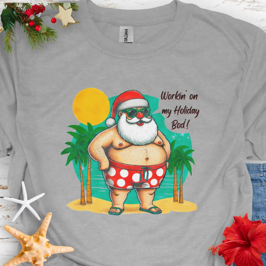 Gray T-shirt with Santa with swim shorts on the beach with text Workin' on my Holiday Bod'!