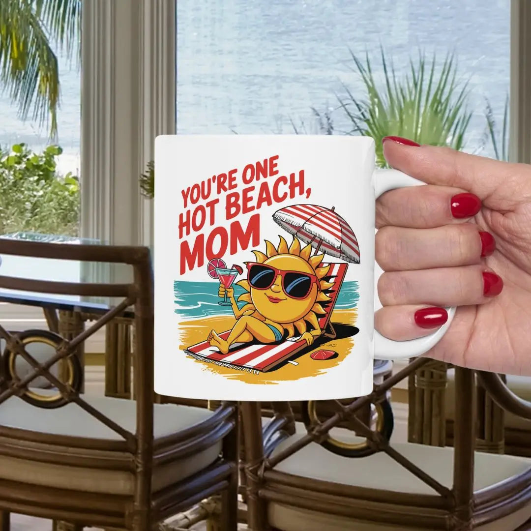 A white 11 oz mug with a sexy sun laying on a beach towel holding a drink on the beach that says You're One Hot Beach Mom.