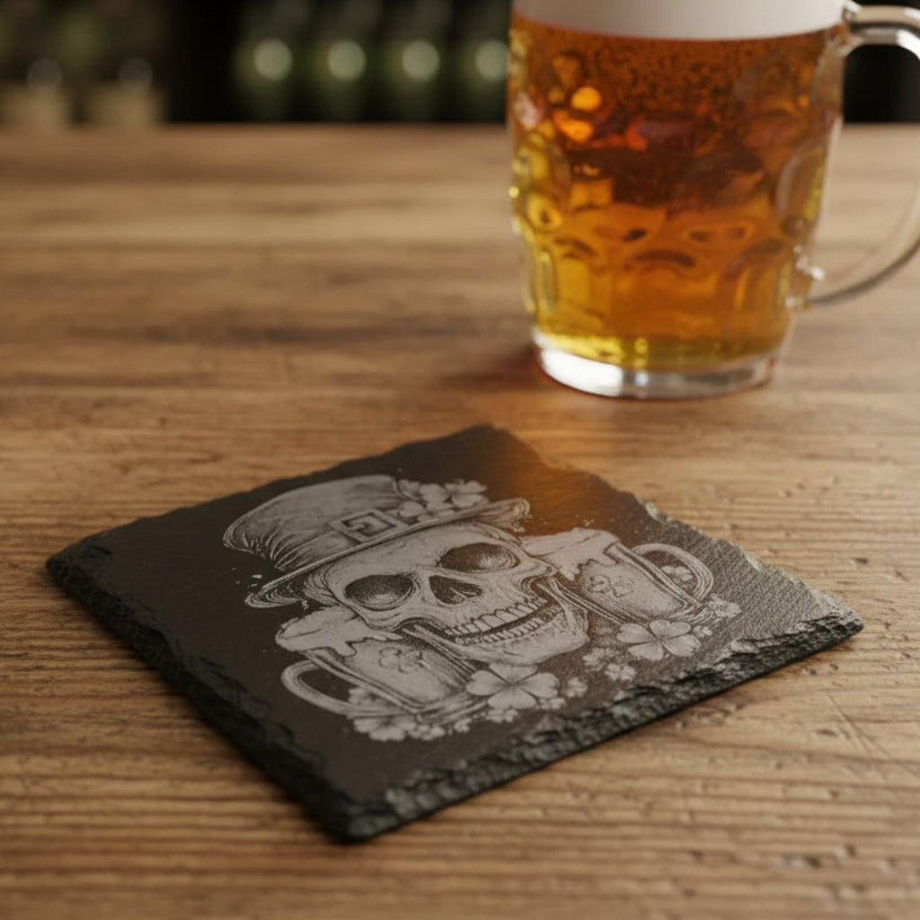 Black 4" slate coaster with skull wearing an Irish top hat with two pint glasses and shamrocks.