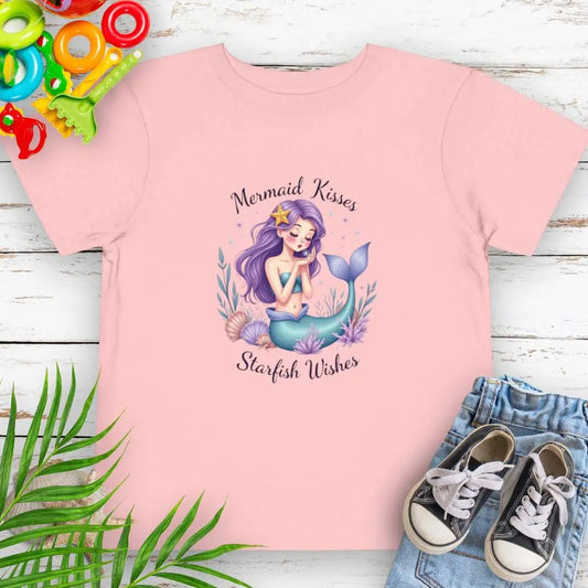 Mermaid Kisses Starfish Wishes Toddler Pink T-shirt featuring a mermaid sitting in sea plants and shells blowing bubbles.