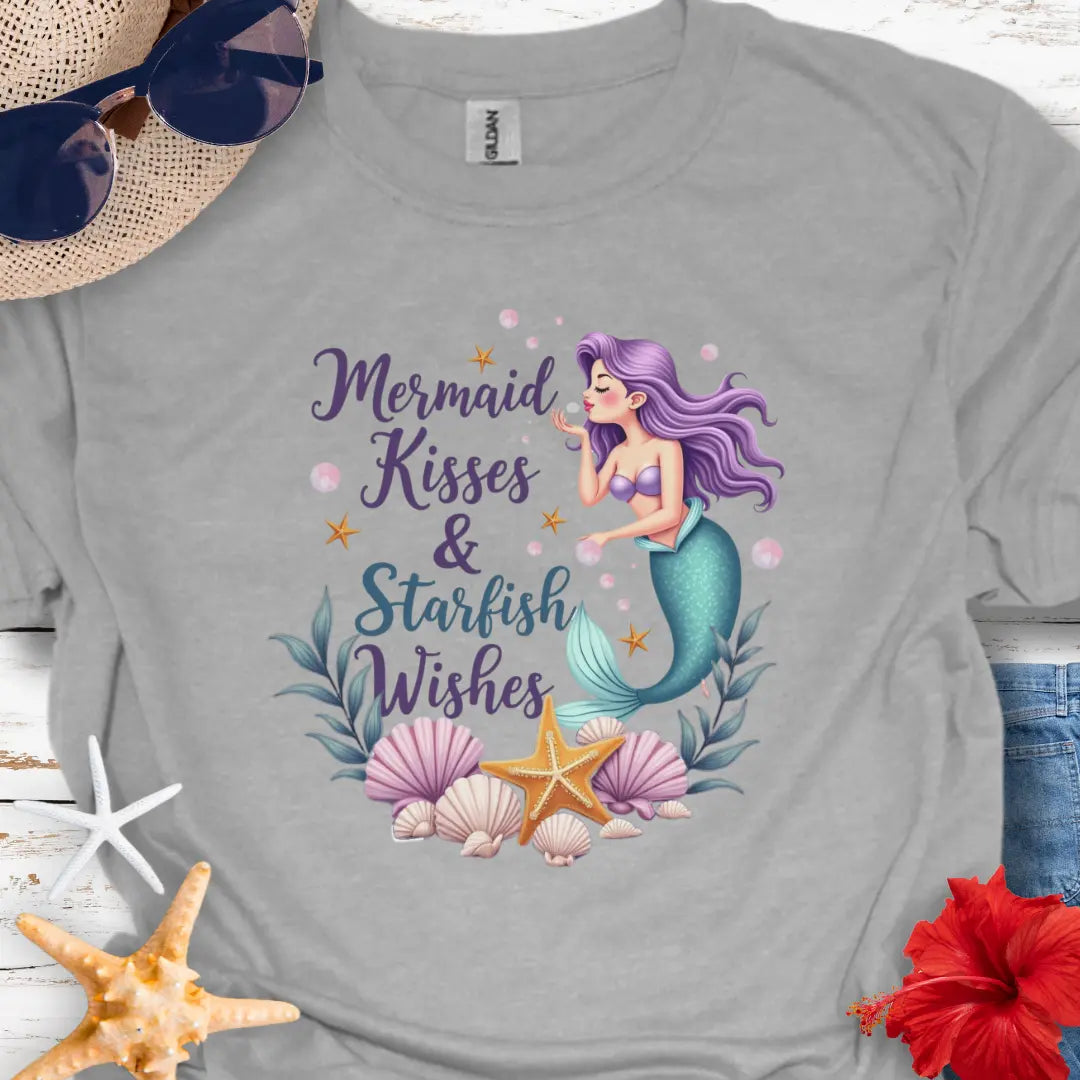 Light gray t-shirt with a graphic of a mermaid blowing kisses surrounded by seashells and the text 'Mermaid Kisses & Starfish Wishes'.