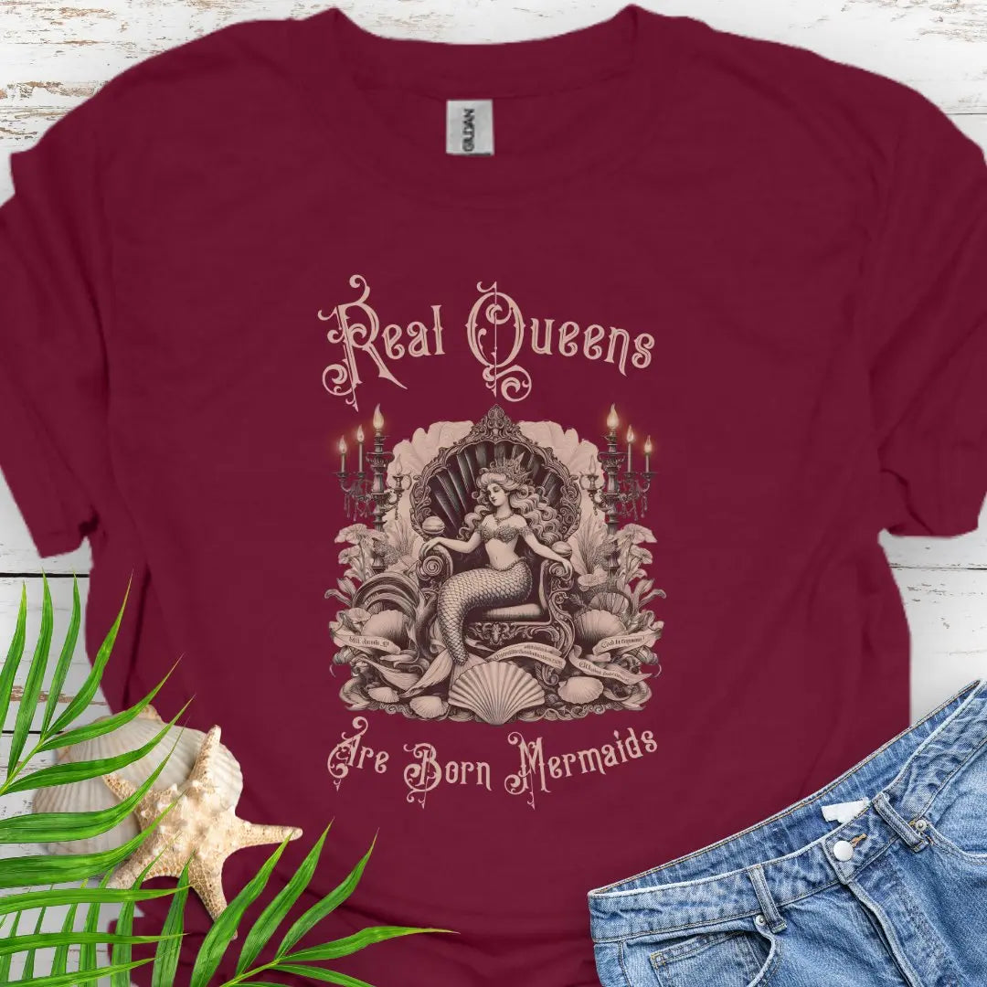 Maroon T-shirt with mermaid in Victorian style chair and surrounding shells and candles with the text Real Queens Are Born Mermaids -perfect for those who believe in mermaid magic and want to showcase their inner queen.