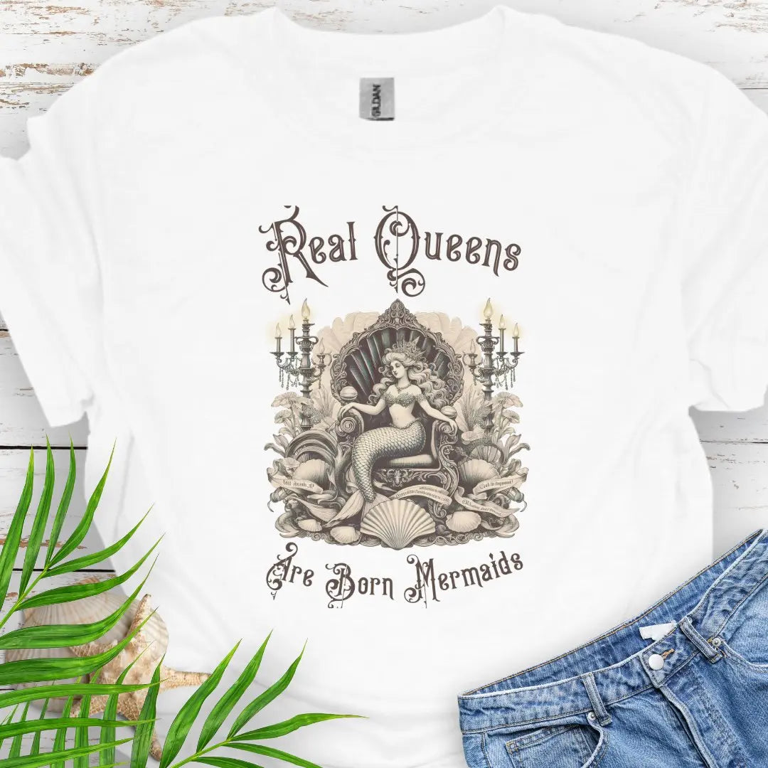 White T-shirt with mermaid in Victorian style chair and surrounding shells and candles with the text Real Queens Are Born Mermaids -perfect for those who believe in mermaid magic and want to showcase their inner queen.