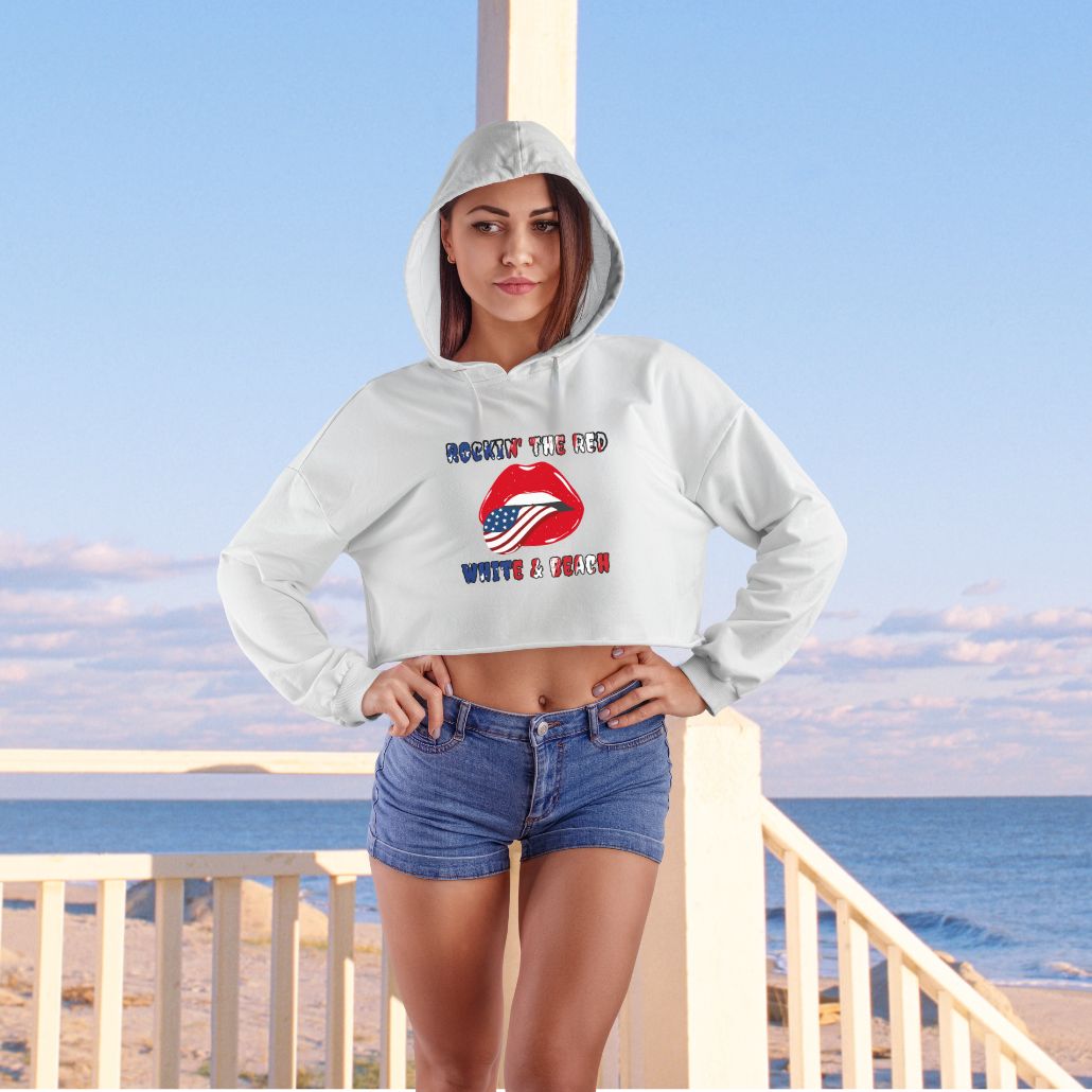 Woman wearing our white Rockin' the Beach Crop Hoodie - Patriotic Fashion for Summer Celebrations Hoodie featuring rolling stone lips with an American flag tongue and text that says Rockin' the Red White and Blue that has a gradient of the flag inside.