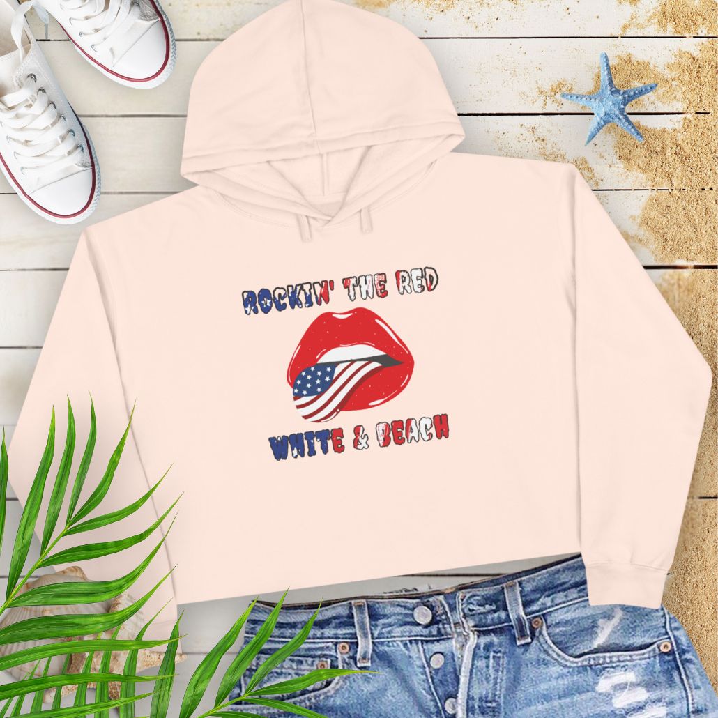 Pale Pink Rockin' the Beach Crop Hoodie - Patriotic Fashion for Summer Celebrations Hoodie featuring rolling stone lips with an American flag tongue and text that says Rockin' the Red White and Blue that has a gradient of the flag inside.