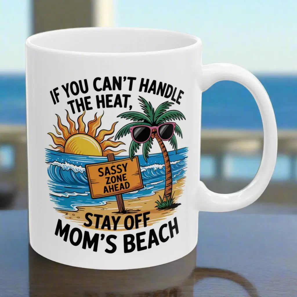 A white 11 oz mug with a beach scene and a beach sign that says Sassy Zone Ahead with the text If You Can't Handle the Heat Stay Off Mom's Beach.