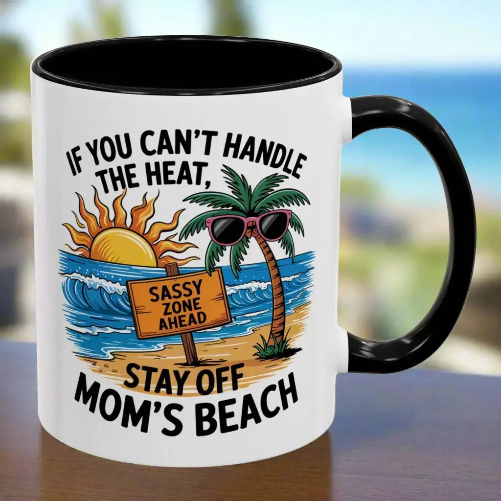 A white 11 oz mug with a black handle and inside with a beach scene and a beach sign that says Sassy Zone Ahead with the text If You Can't Handle the Heat Stay Off Mom's Beach.